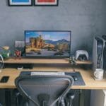 Técnico de Suporte e +Remotas, VA/VR de R$ 750 e +benefícios A contemporary home office desk featuring a computer setup with gaming peripherals and decor.