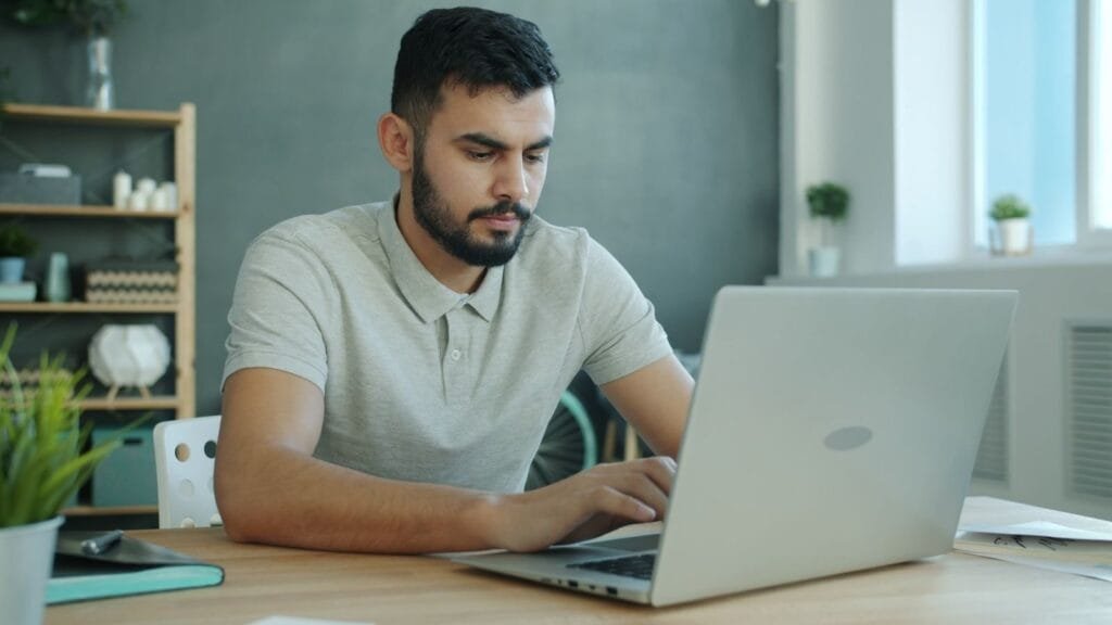 Vagas 100% Remotas na Bernoulli Focused young man typing on a laptop in a contemporary office setting.