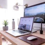 Vagas 100% remotas na Techne MacBook Pro on table beside white iMac and Magic Mouse