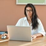 Analista de BI e +Remotas, VA/VR de R$ 950 A woman wearing glasses works on a laptop