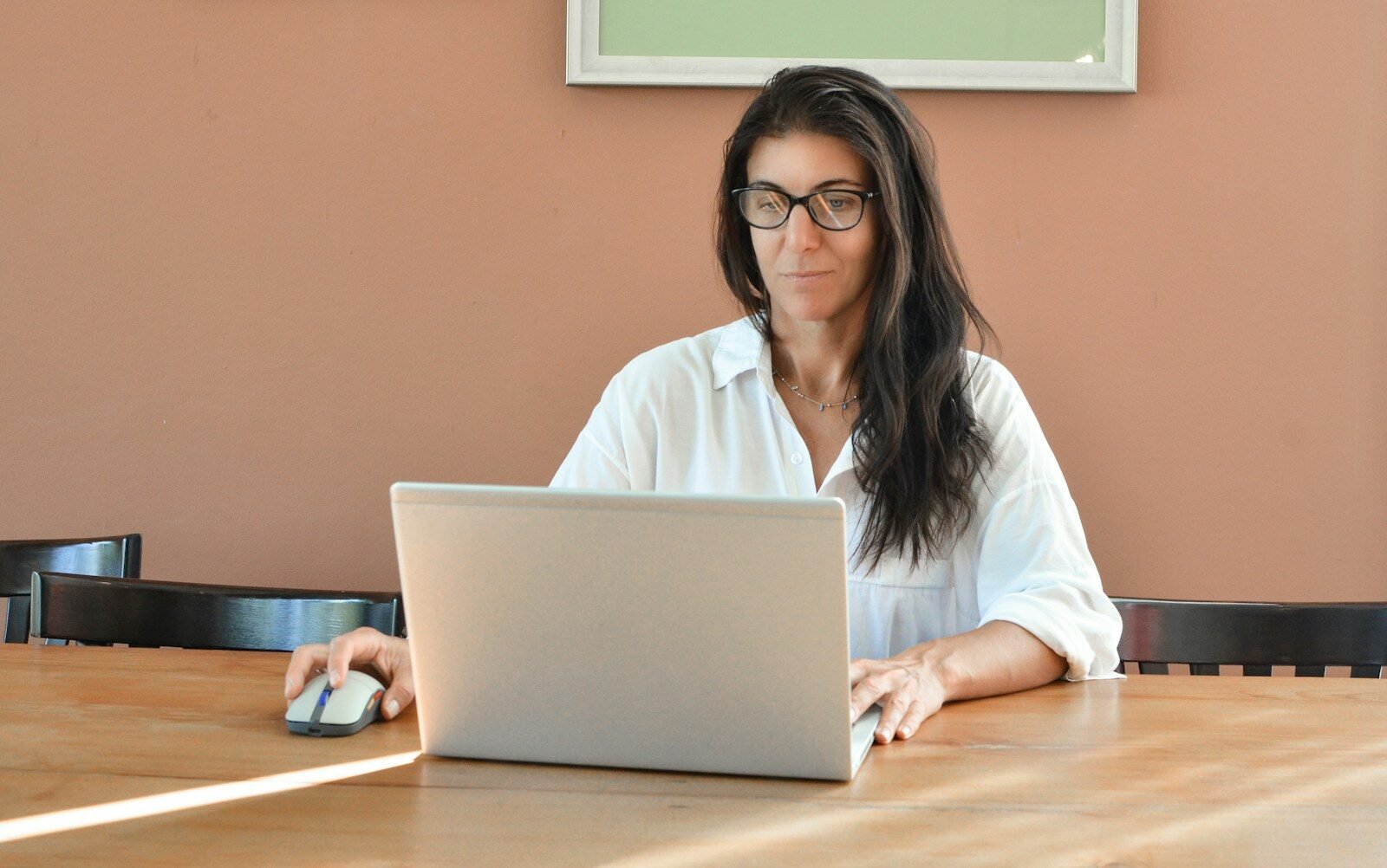 Analista de BI e +Remotas, VA/VR de R$ 950 A woman wearing glasses works on a laptop