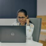 Analista Administrativo e +Remotas com VA/VR de R$ 700,00 a woman sitting in front of a laptop computer
